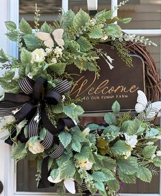 a welcome sign on the front door of a house decorated with greenery and flowers