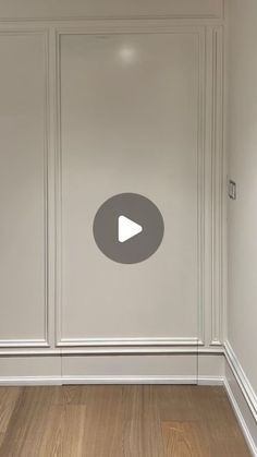 an empty room with wood floors and white walls, showing the video player's play button