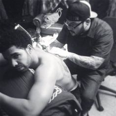 a black and white photo of a man getting his arm tattoo done by another man