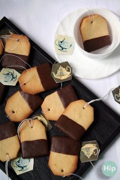 some cookies are on a black tray next to a cup and saucer