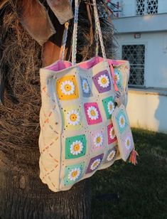 a crocheted bag hanging from a palm tree in front of a white house