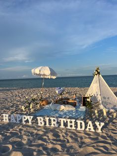 there is a birthday sign on the beach with an umbrella in the sand near it