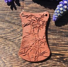 a piece of clay sitting on top of a wooden table next to flowers and plants