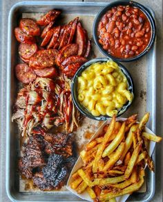 a tray filled with meat, beans and macaroni next to other food items