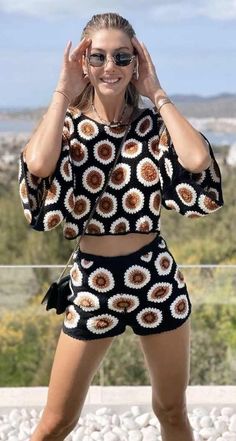 a woman is posing for the camera with her hands on her head and wearing sunglasses