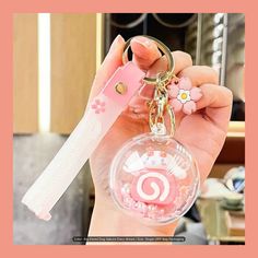 a hand holding a key chain with a pink case on it and a white plastic object in the middle