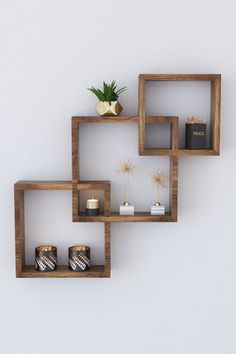 three wooden shelves with candles on them against a white wall in the shape of hexagonal cubes