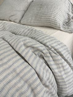 an unmade bed with blue and white striped sheets