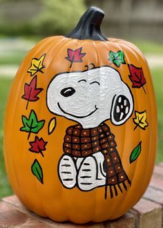 a painted pumpkin with a snoopy dog on it's face and leaves around its neck