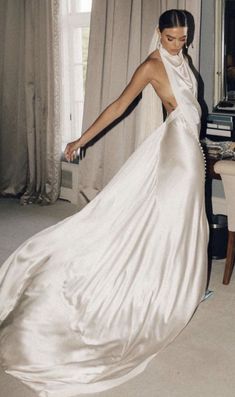 a woman in a long white dress standing next to a table