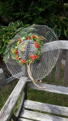 an old fashioned hat is sitting on a wooden bench in the grass next to some bushes