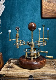 a wooden table topped with a metal and wood clock on top of a blue wall