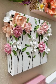 some pink and white flowers are hanging on the wall