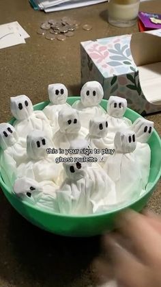 a green bowl filled with marshmallows and ghost faces