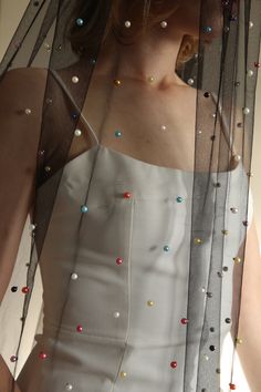 a woman wearing a white dress with multicolored beads on it's veil