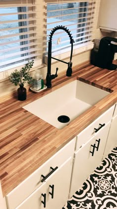 a kitchen sink sitting under a window next to a faucet and counter top