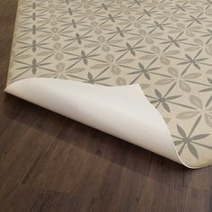 a close up of a floor covering on a wooden floor with a flower pattern design