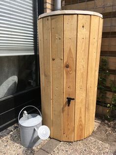 a wooden barrel next to a bucket on the side of a building with a window