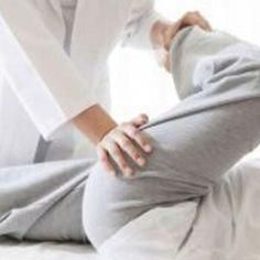 a woman in white shirt and grey pants sitting on bed