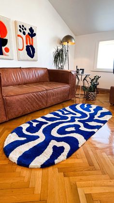 a brown leather couch sitting on top of a hard wood floor next to a blue and white rug