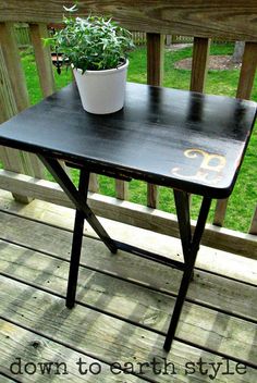 a small table with a potted plant on it sitting on a porch next to a fence