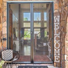 a welcome sign is on the front door of a home with stone walls and glass doors