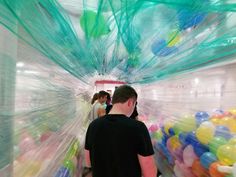 a man standing in a room filled with lots of different colored balls and streamers