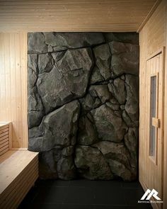 an indoor sauna with large rocks on the wall and benches in front of it