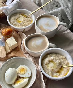 four bowls of oatmeal and eggs on a table