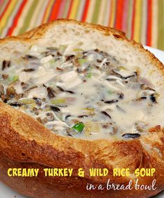 creamy turkey and wild rice soup in a bread bowl on a striped tablecloth with text overlay