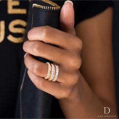 a woman is holding a black case with three rings on her finger and wearing a gold ring