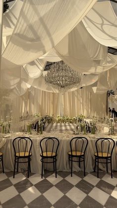 a banquet hall with tables and chairs covered in white draping, chandeliers hanging from the ceiling