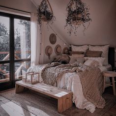 a bed sitting under a window next to a wooden table and chair in a bedroom