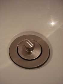 a white sink with a chrome faucet on the side and a drain in the middle