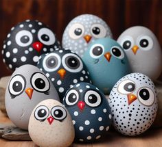 an assortment of painted rocks with owls sitting on top of each other in front of a wooden background