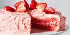 there is a cake with pink frosting and strawberries on the top, ready to be eaten