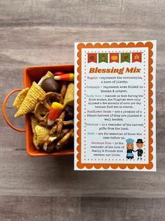 an orange bowl filled with cereal and candy on top of a wooden table next to a card