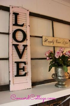 a shelf with flowers and two wooden signs on the wall above it that say love