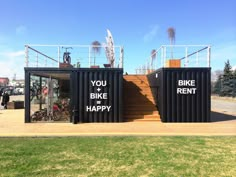 two shipping containers with the words you bike and happy written on them are in front of a grassy area