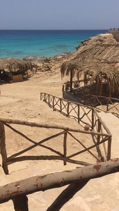 a beach with thatched umbrellas and steps leading to the ocean