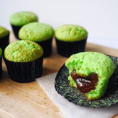 cupcakes with green frosting and jelly in the middle on a wooden tray