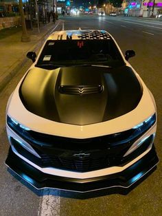 the front end of a white and black car parked on the side of the road