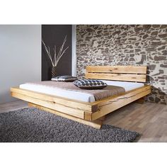 a bed that is made out of wood and has pillows on the top of it