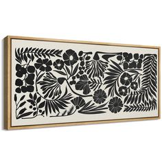 a black and white wall hanging with flowers on the bottom, in front of a wooden frame