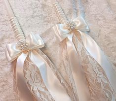 two wedding garters with bows and pearls on the side, laying on a bed