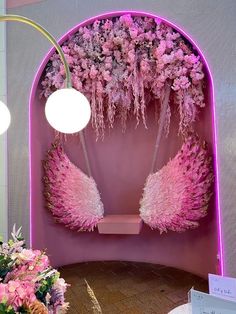 pink flowers and angel wings are on display in a room with purple walls, round lights, and white lamps