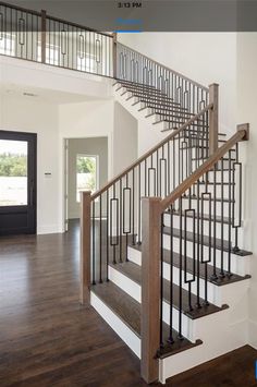 a staircase in a house with wood floors and railings on both sides, leading to the second floor