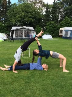 two people doing yoga on the grass in front of their camper's tents