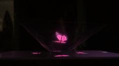 a pink butterfly sitting on top of a purple object in the middle of a dark room