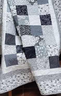 a black and white quilt sitting on top of a wooden table next to a chair